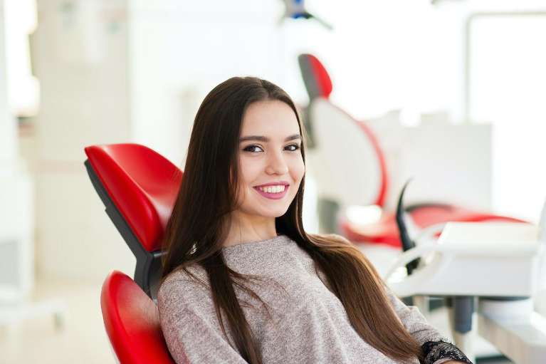 Girl in dentist chair with brown hair smiling, ashburn va